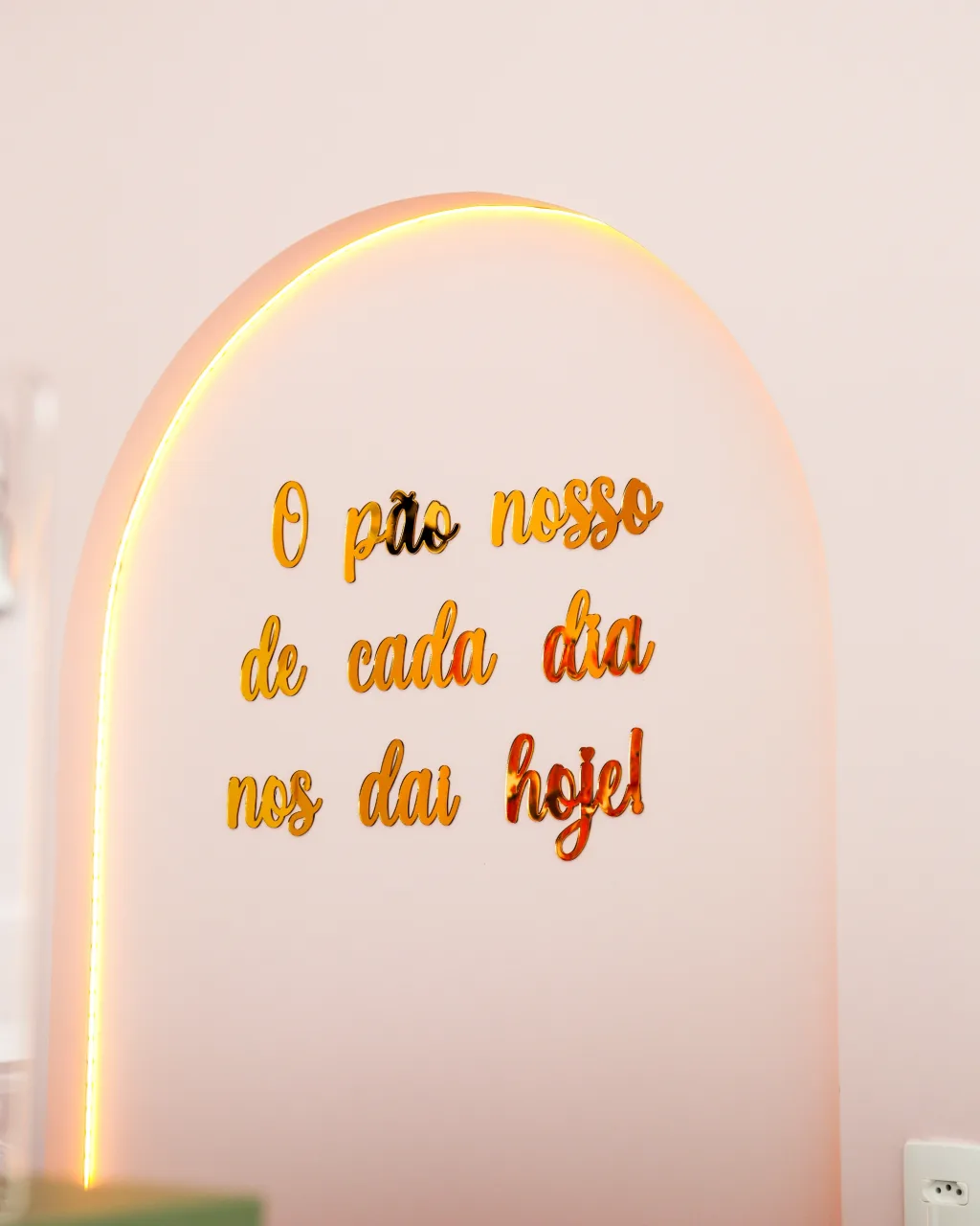 Arco iluminado na parede, com a frase “O pão nosso de cada dia nos dai hoje!” em letras douradas.